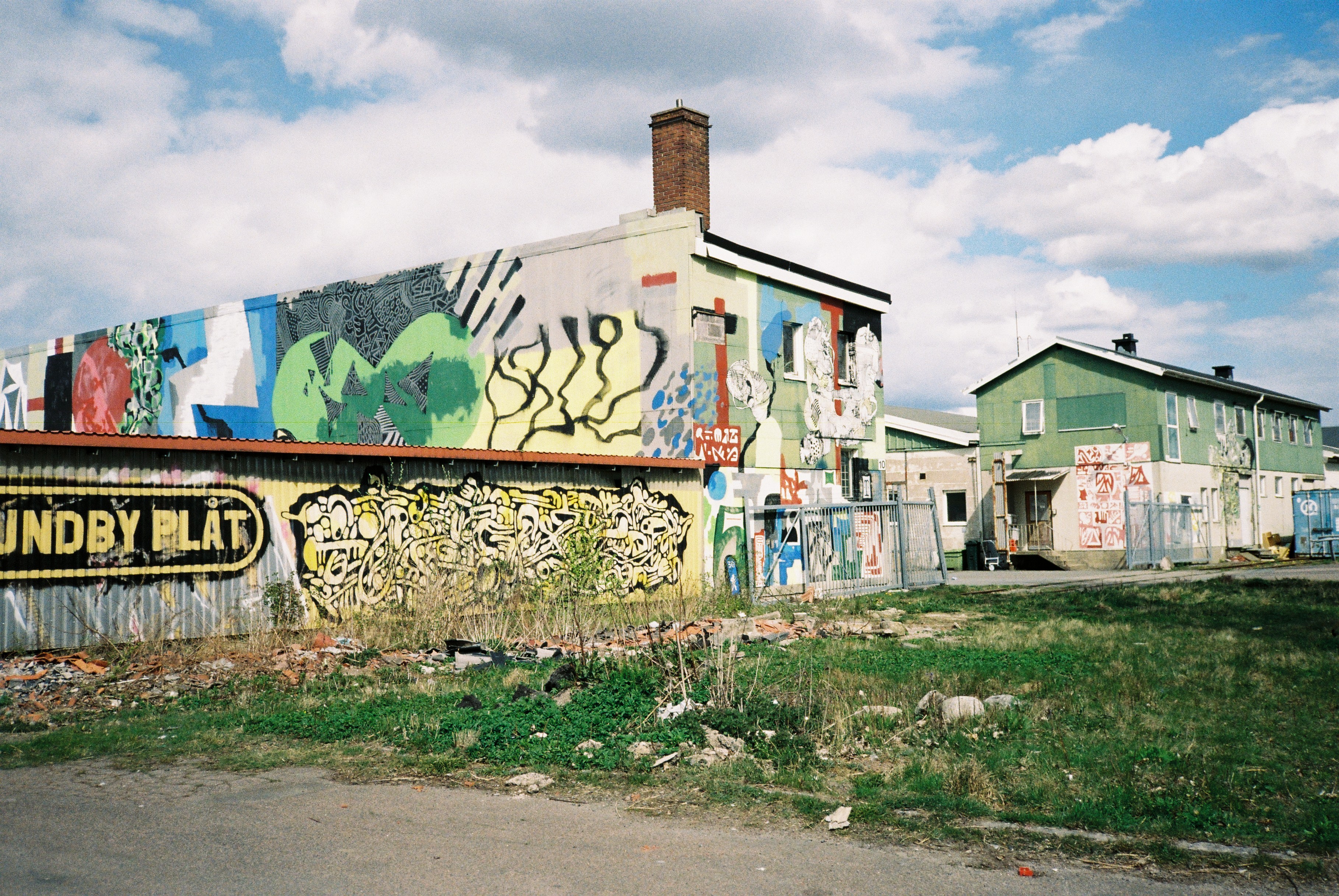 Ringön street view: graffitied warehouses with a green house behind, the Lundby Plåt sign visible — the industrial harbour area where the fieldwork took place.